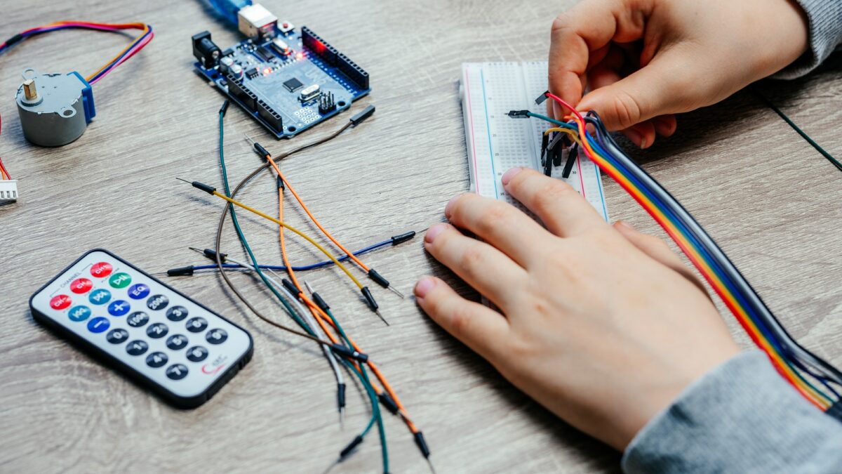 A child plugging cables to sensor chips while learning arduino coding and robotics