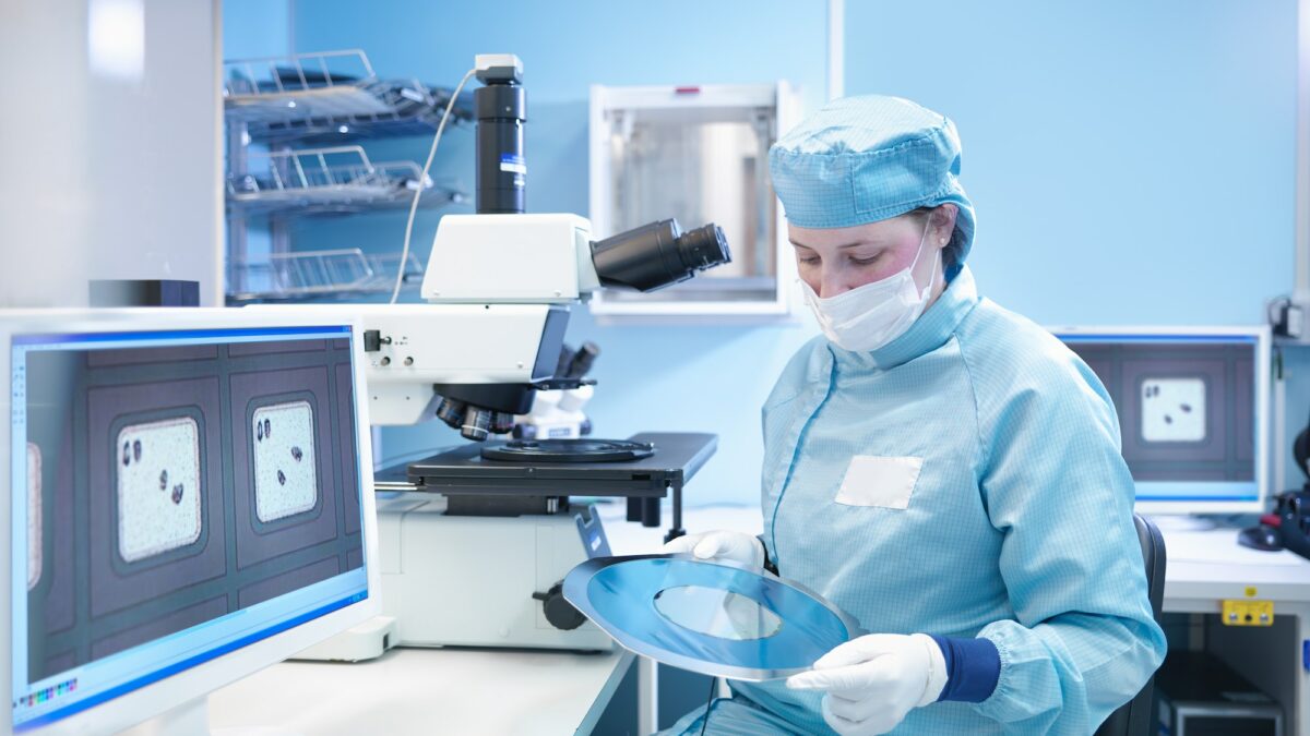 Electronics worker in clean room with silicon wafer