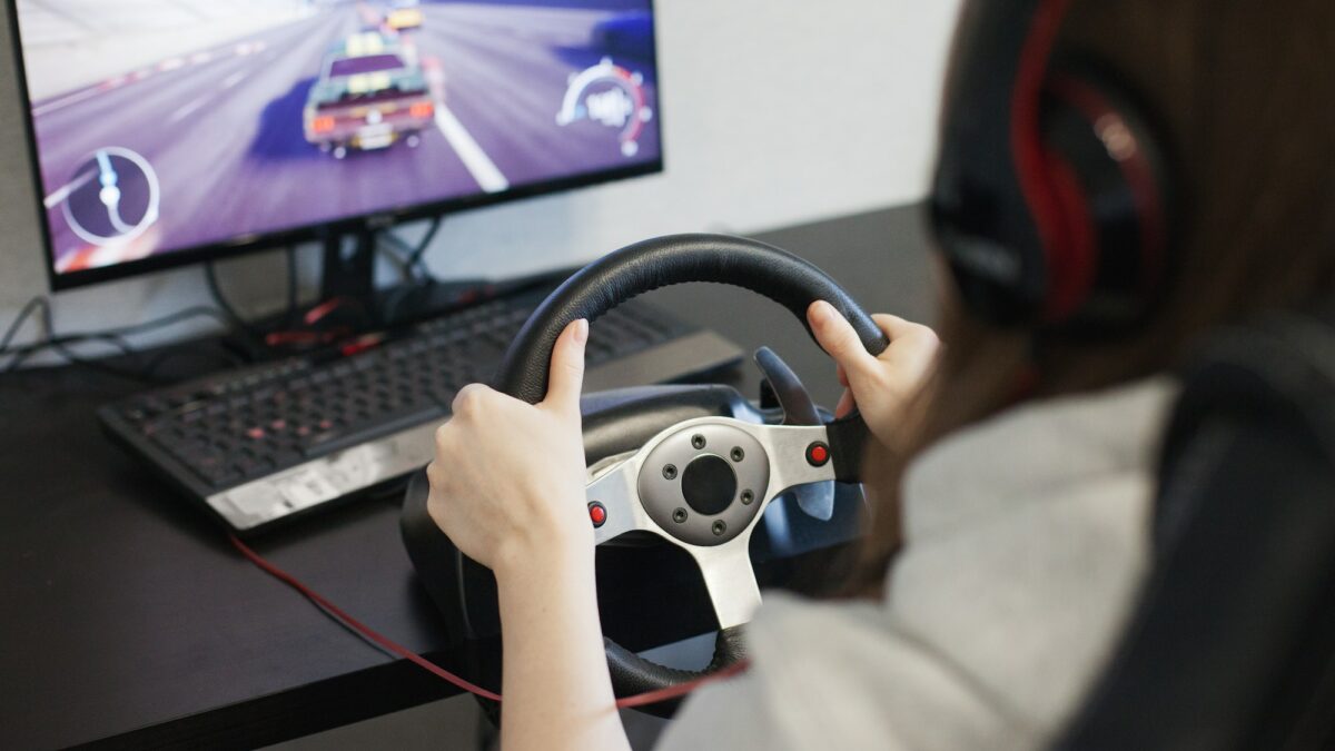 Woman playing a video game, using steering wheel and driving, using computer at home