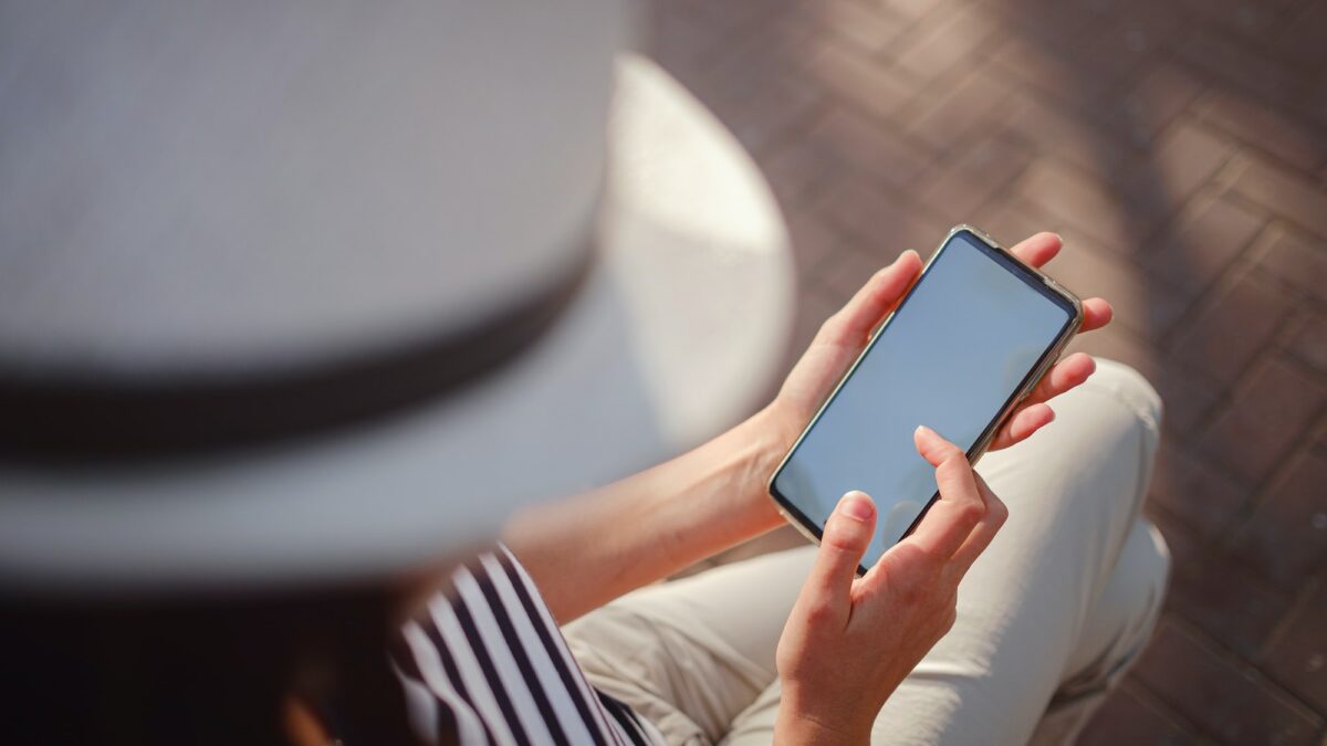 A woman wearing a protective mask looks at her smartphone display