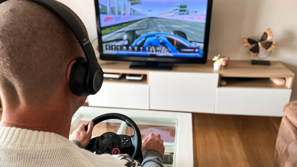 Man playing a video game at home; driving, steering wheel, car race, computer game on television