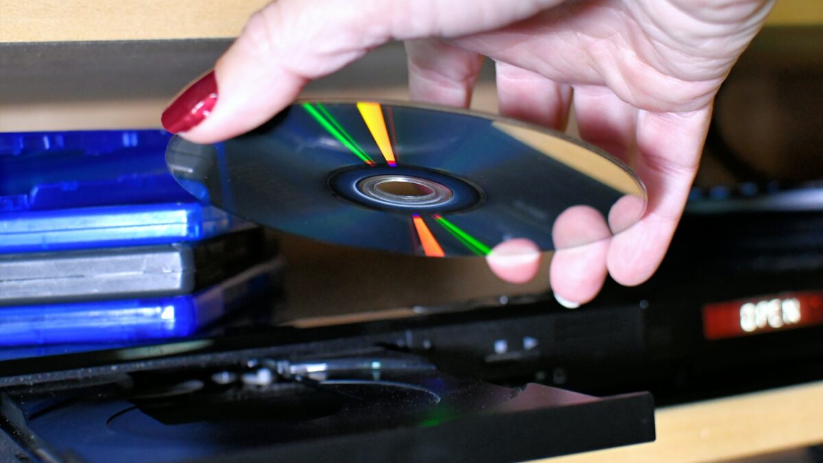 Woman putting a Blu-ray DVD disc into a player for movie night.