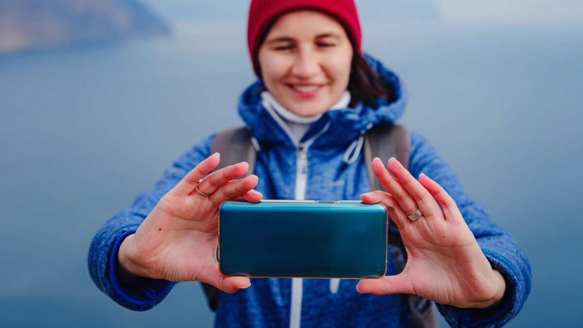woman take photo of sea on smartphone