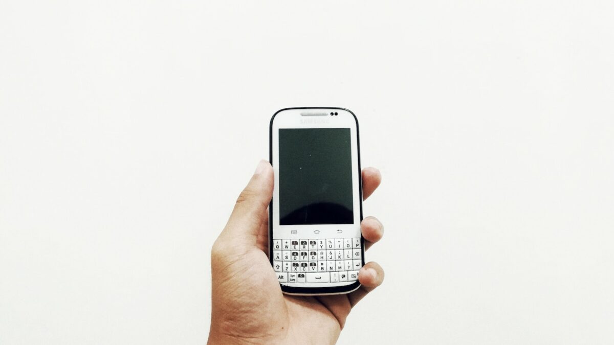person holding white QWERTY phone