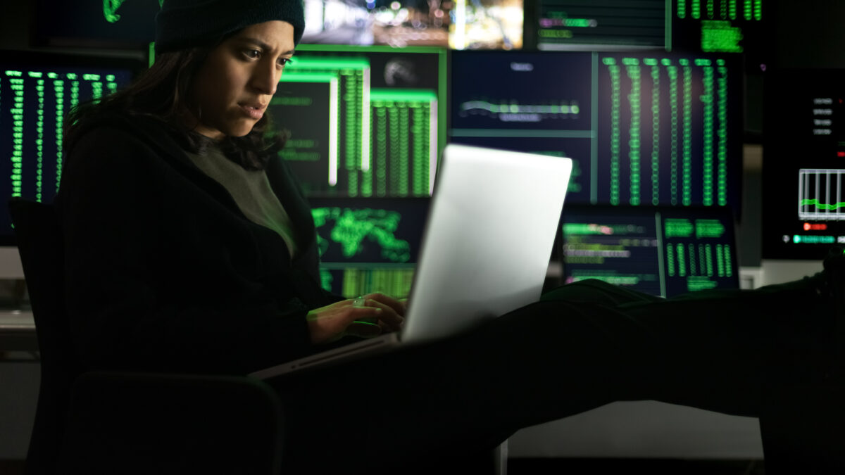 Latina female hacker using laptop to organize malware attack on global scale.