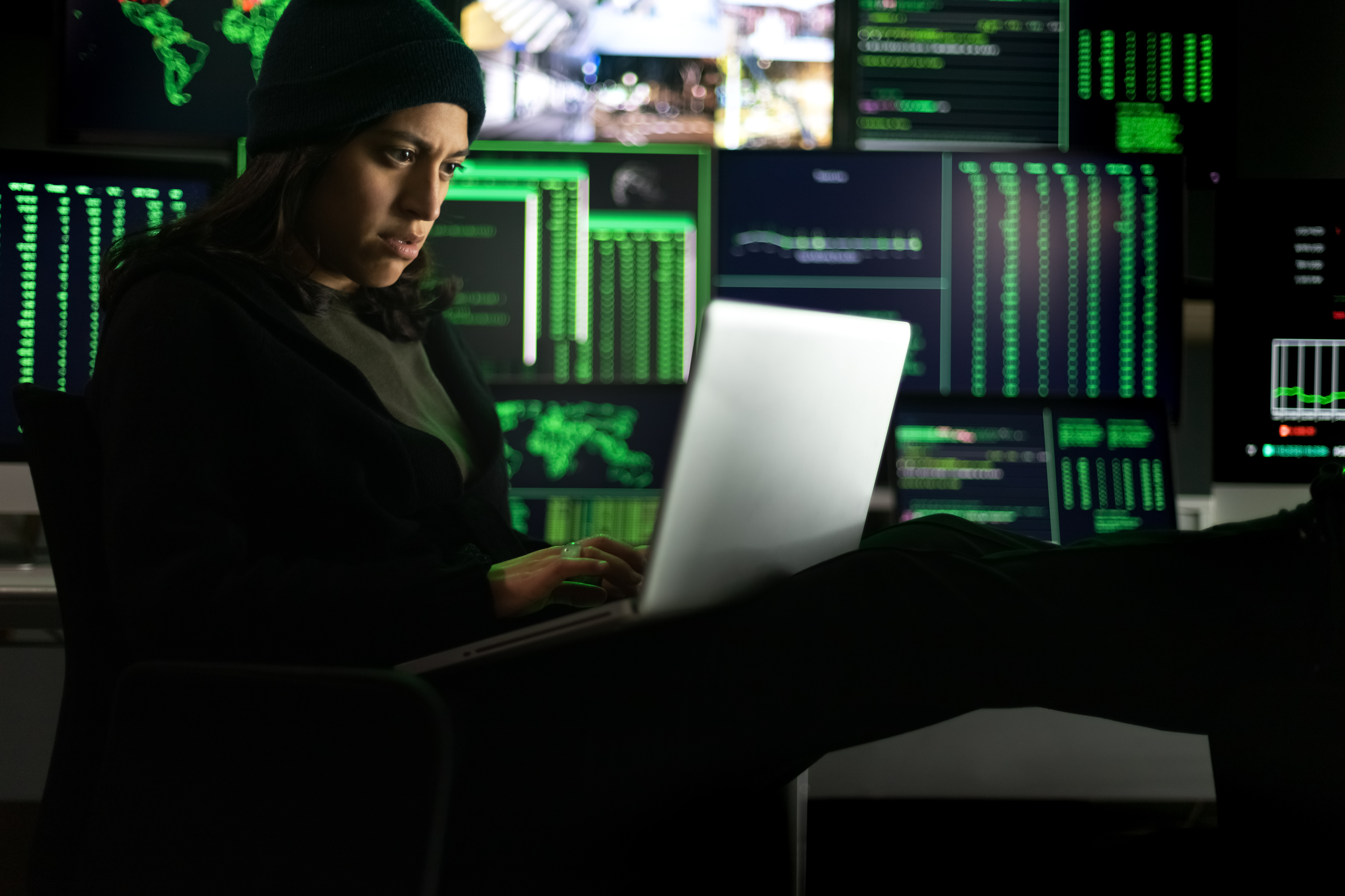 Latina female hacker using laptop to organize malware attack on global scale.