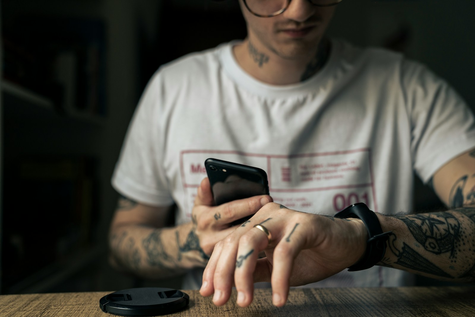 man in white crew neck t-shirt holding black smartphone