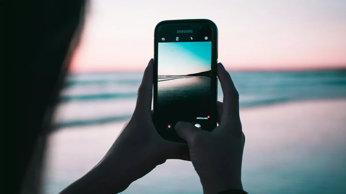 shallow focus photography of person taking photo body of water